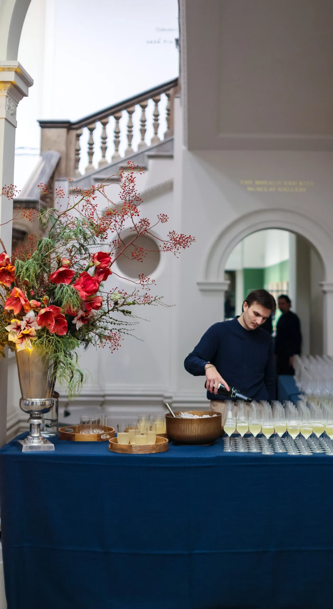 Royal Academy of Arts: a drink table at the base of the staircase with server pouring glasses of drinks in stem glasses