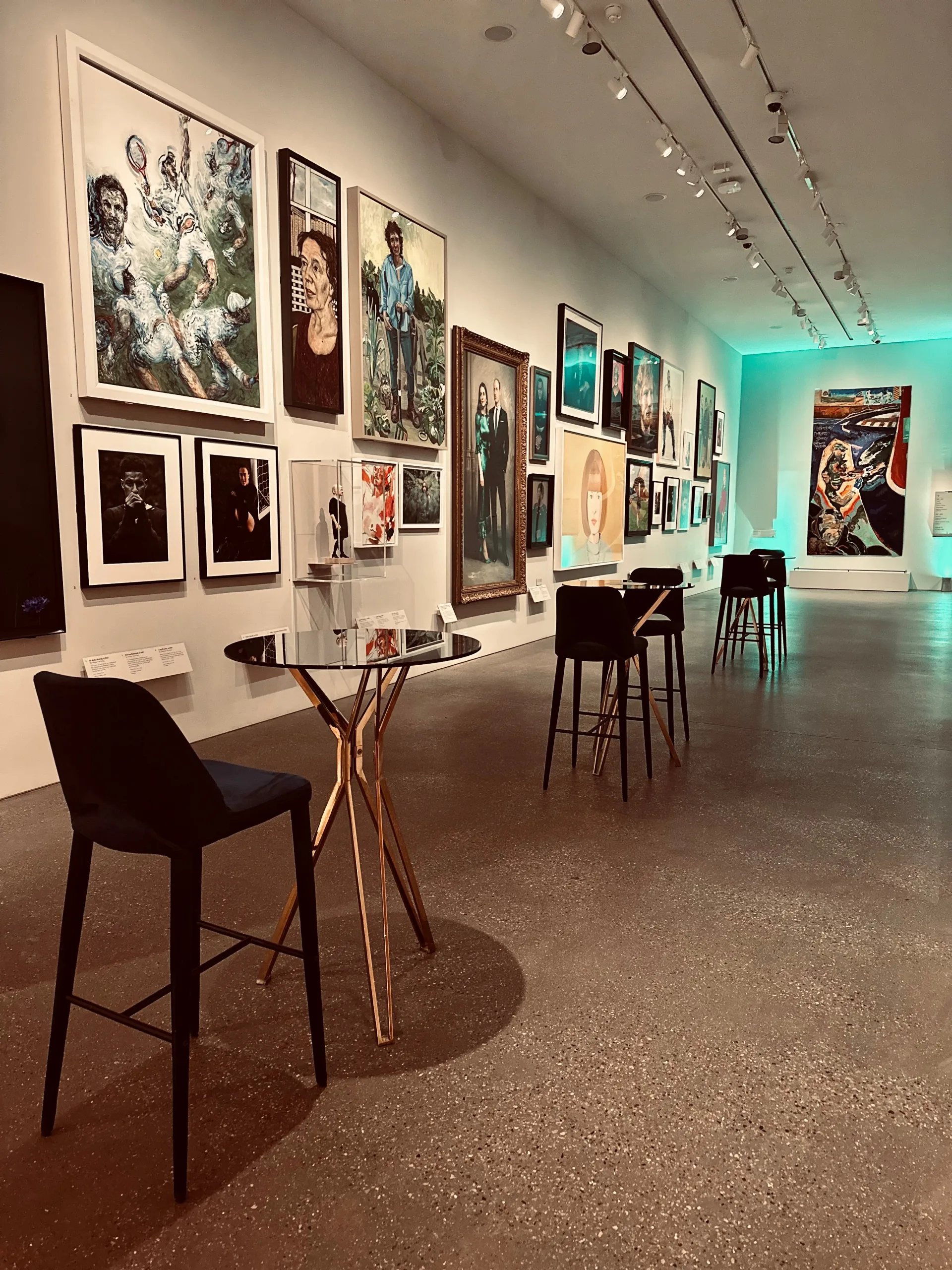 National Portait Gallery contemporaries gallery with various large portraits and small high round tables with tall chairs