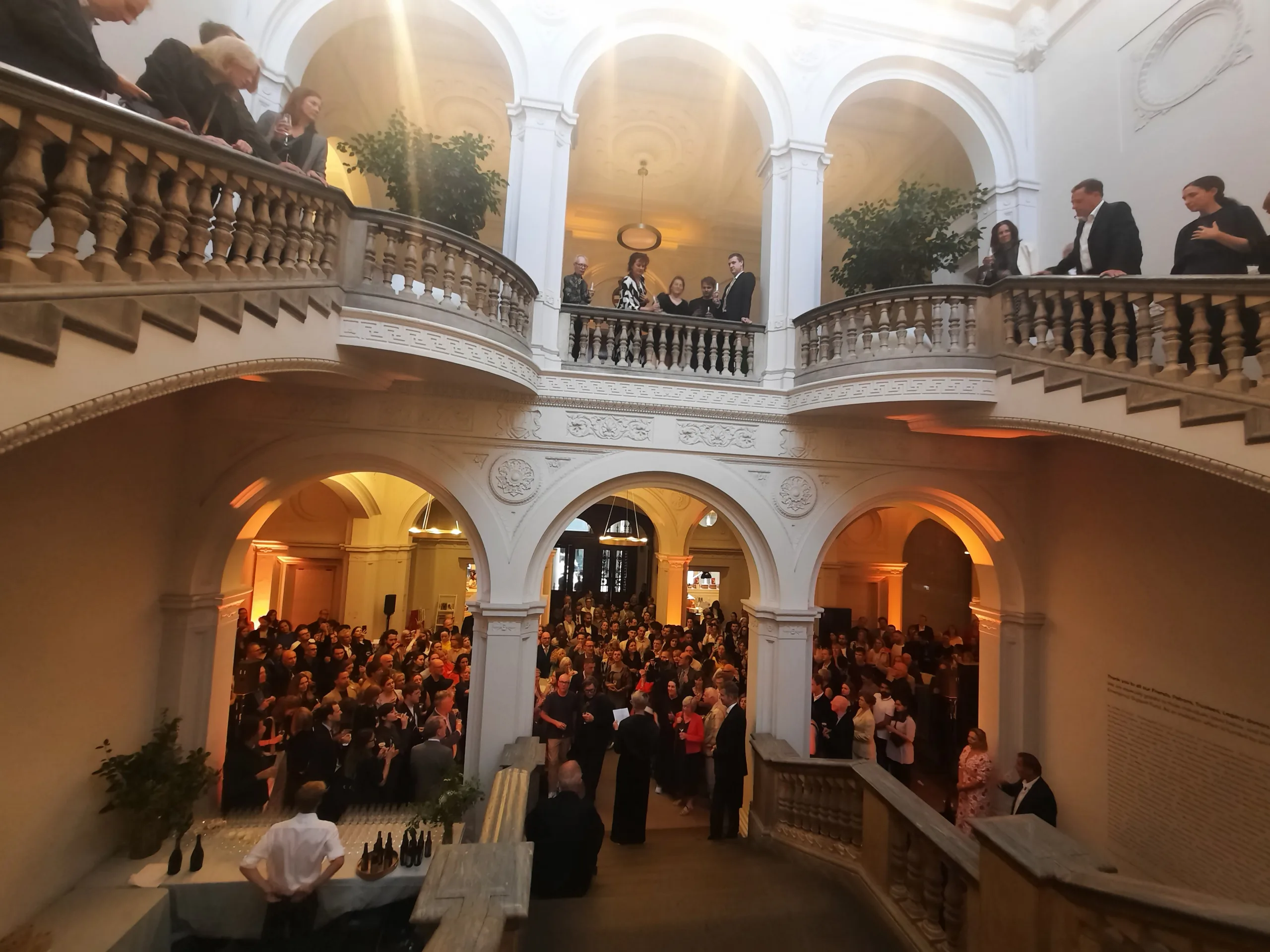 Royal Academy of Arts stairway view of an event with people on the stairs, second floor balcony and in the lower area