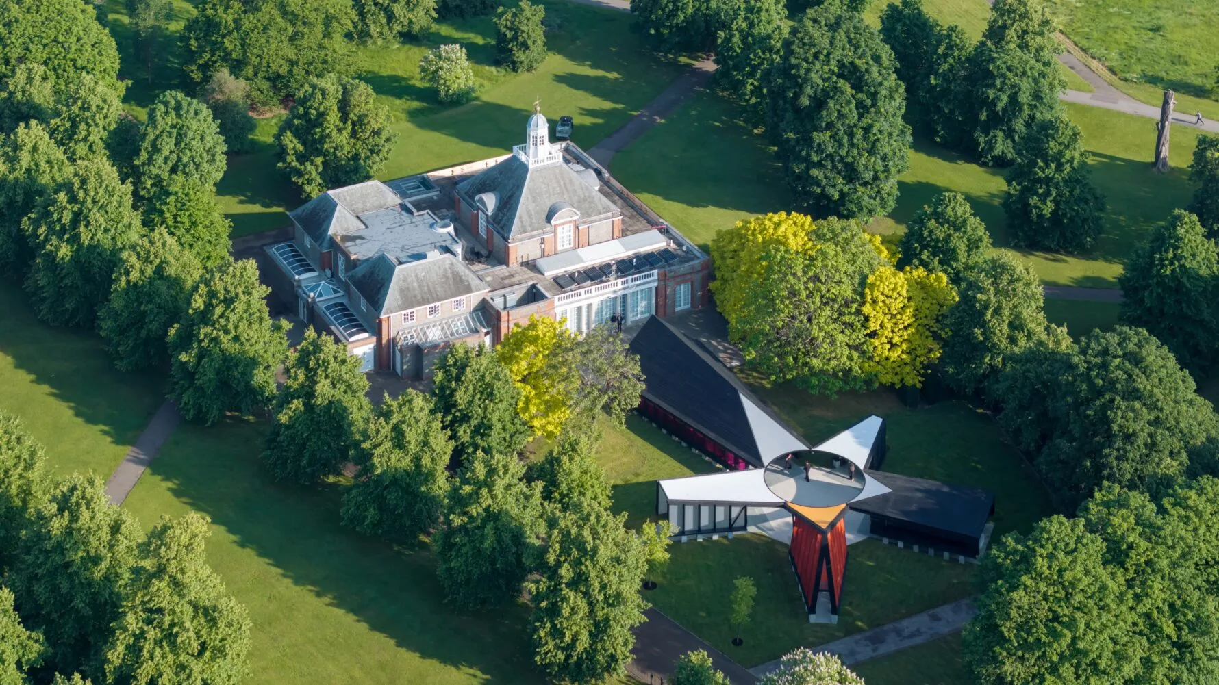 Aerial view of the Serpentine Gallery showing the main gallery building surrounded by trees, and the five point pavilion.