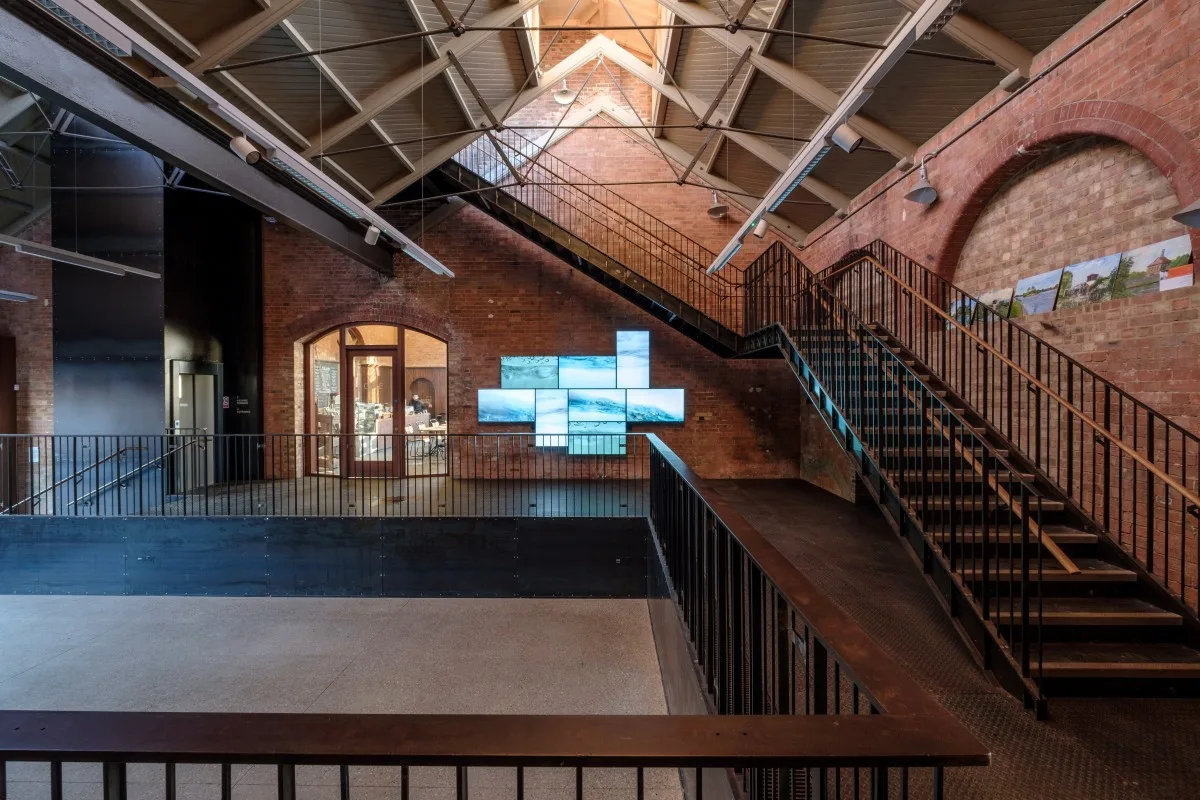 Interior rooftop area of building, featuring visible beams and red brick walls.